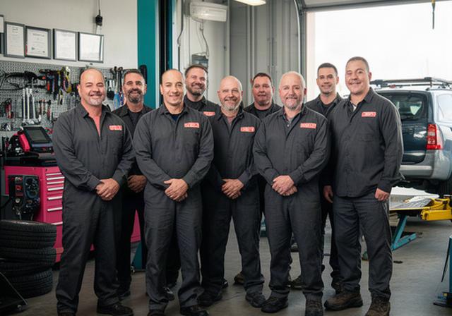 Automotive repair team in work uniforms standing together inside their Winnipeg service workshop